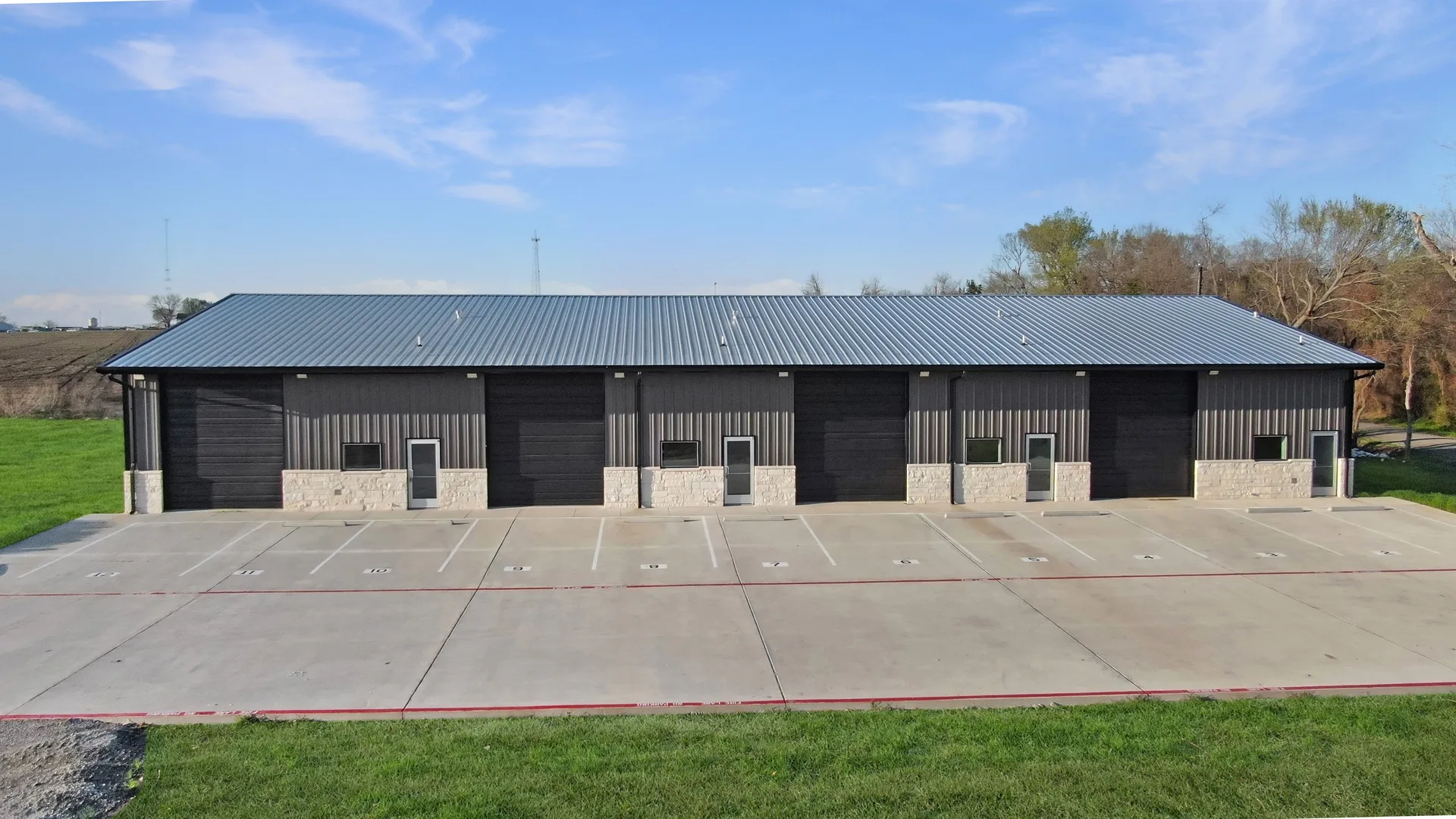 Front elevation of Triple C Business Park showing multiple commercial bay entrances and paved parking apron