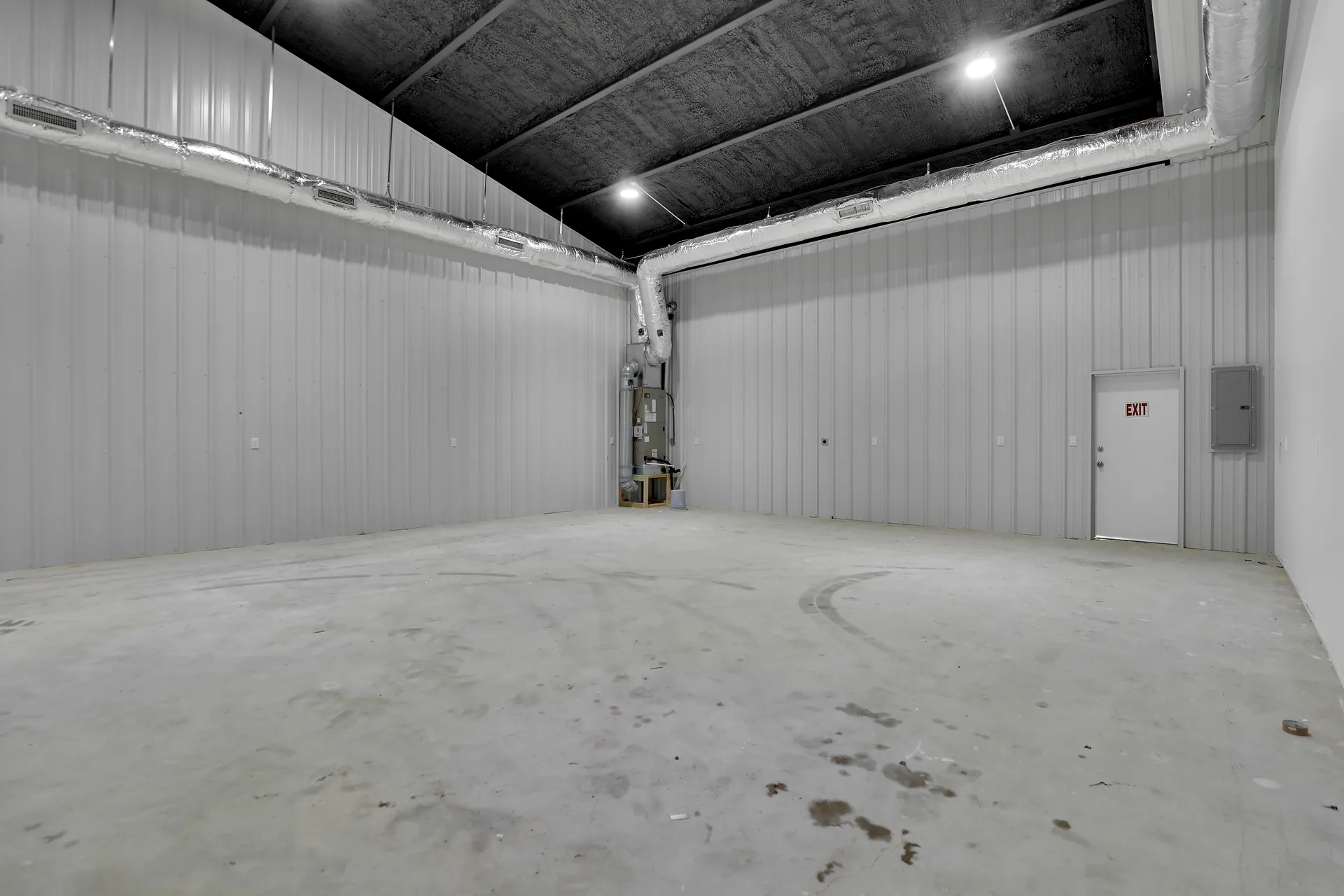 Industrial warehouse interior with high ceilings, metal panel walls, overhead lighting, and open floor space