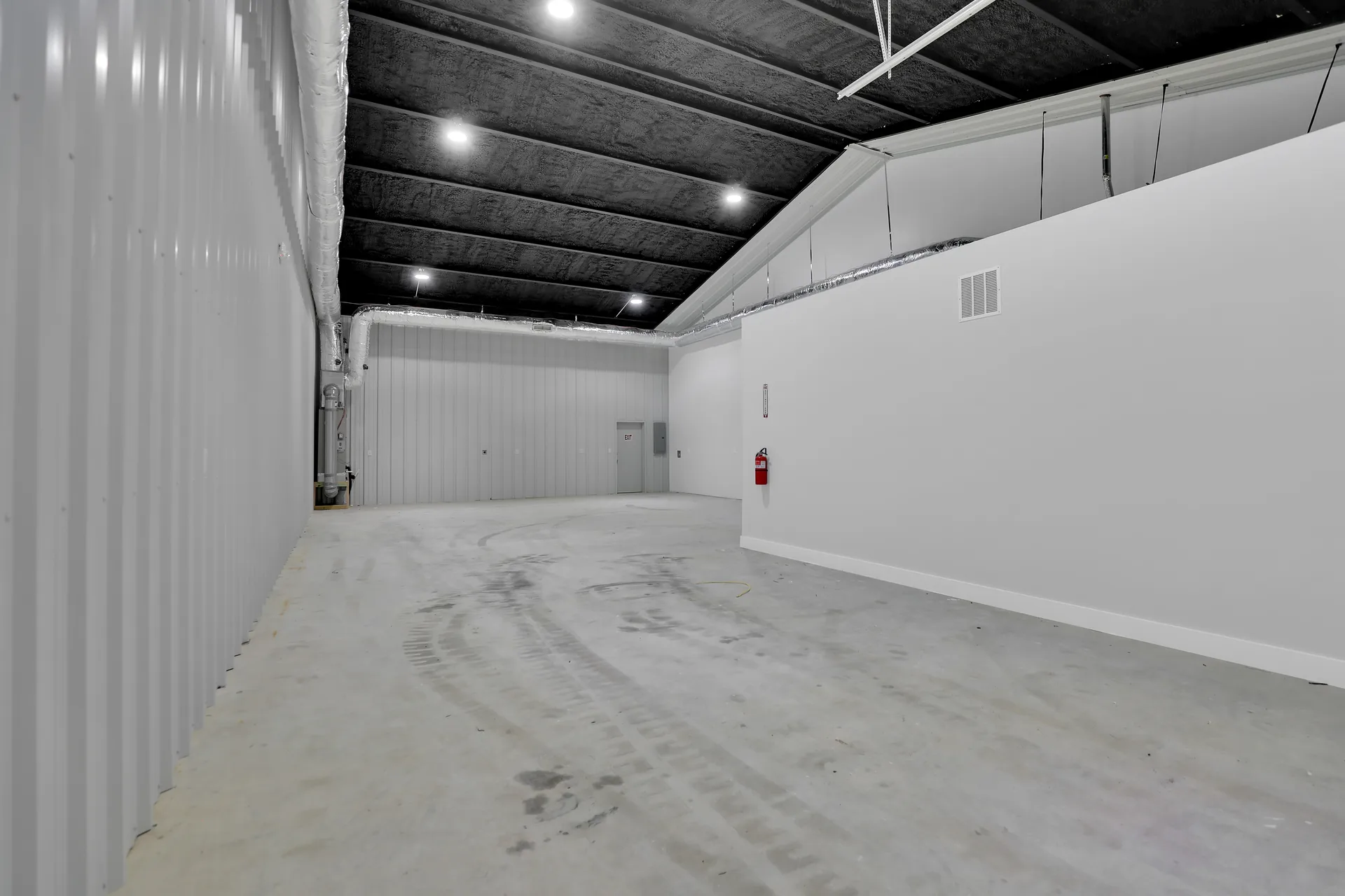 Long warehouse bay at Triple C Business Park with metal wall panels, high ceiling, overhead lights, and open work area