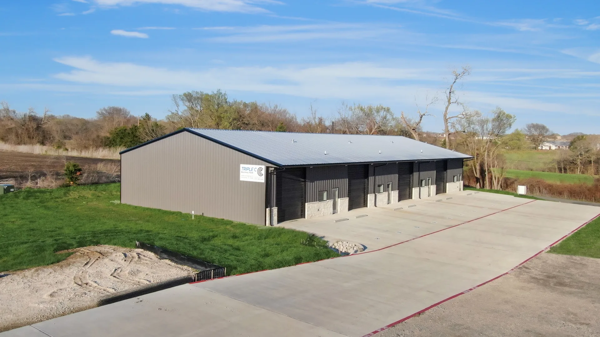 Exterior drone view of the Triple C Business Park metal building with driveway, parking, and landscaped frontage