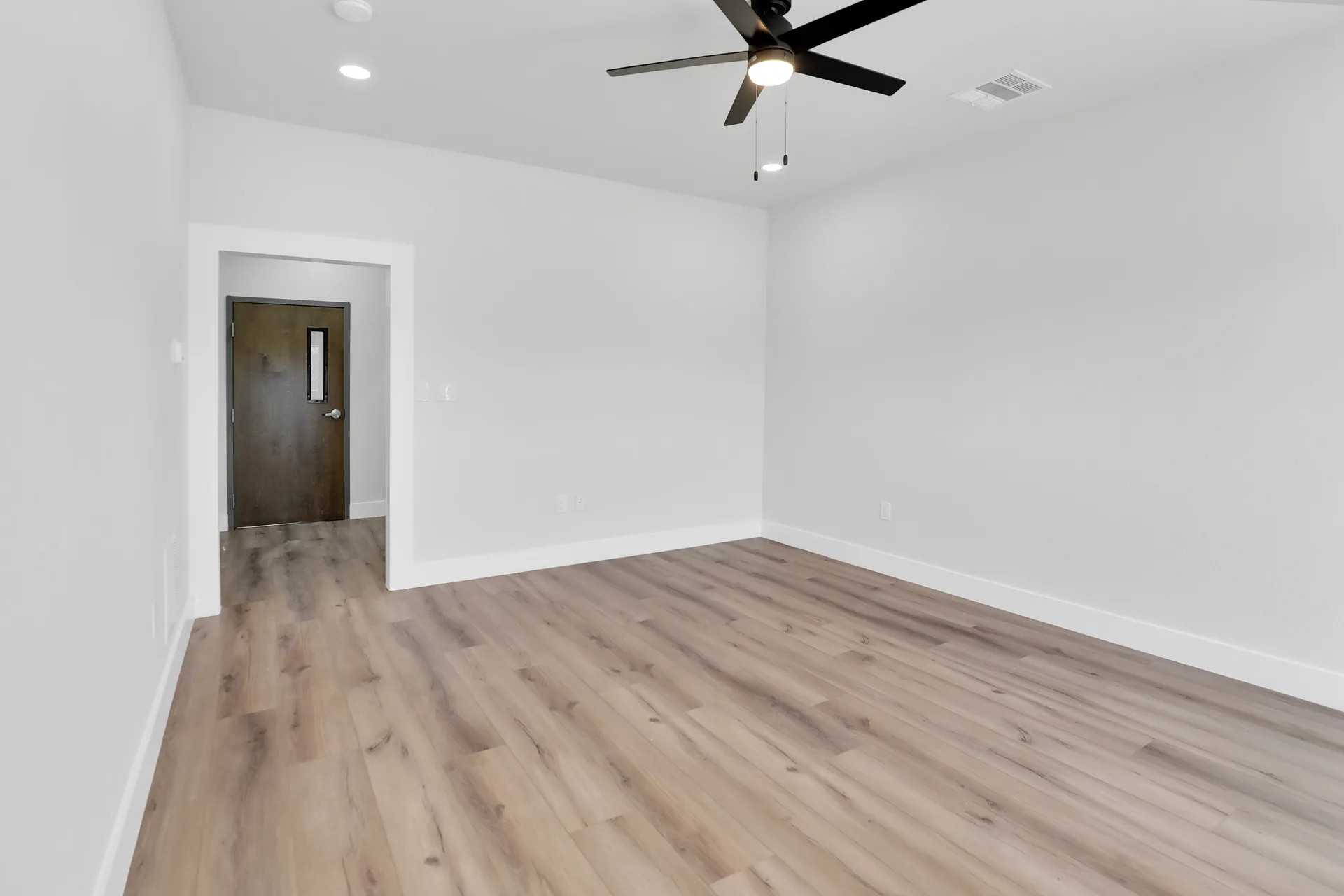 Private office interior with wood-look flooring, white walls, and interior access door at Triple C Business Park